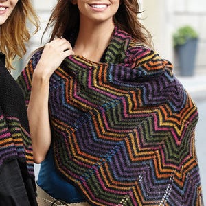 Puede incluir: Un chal de punto colorido con un patr&oacute;n de chevron en tonos de negro, naranja, morado, verde y marr&oacute;n. El chal est&aacute; drapeado sobre los hombros de una persona que lleva pantalones vaqueros azules y un cintur&oacute;n marr&oacute;n.