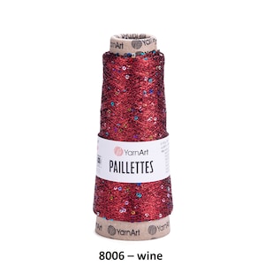 May include: A spool of red metallic yarn with colorful sequins, labeled "YarnArt Paillettes 8006 - wine".