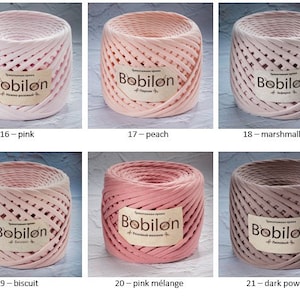 K&ouml;nnte beinhalten: Sechs Spulen mit rosa, pfirsichfarbenem und braunem Baumwollgarn mit der Aufschrift "Bobilon". Das Garn ist in zwei Reihen mit jeweils drei Spulen angeordnet. Die Spulen sind alle gleich gro&szlig; und gleich geformt und alle mit der gleichen Art von Garn gewickelt. Das Garn ist ein weiches, flauschiges und strukturiertes Baumwollgarn.