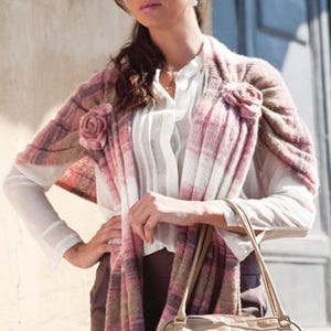 Puede incluir: Una mujer lleva una chalina a rayas rosa y blanca con un bolso de cuero marr&oacute;n. La chalina tiene un dise&ntilde;o floral y est&aacute; drapeada sobre una blusa blanca.