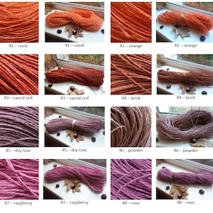 Op de afbeelding: Een verzameling van 10 bollen handgeverfde, natuurlijke vezelgaren in verschillende tinten rood, roze en oranje. Het garen is gerangschikt in twee rijen van vijf bollen elk. Elke bol is gelabeld met een nummer en een kleurnaam.