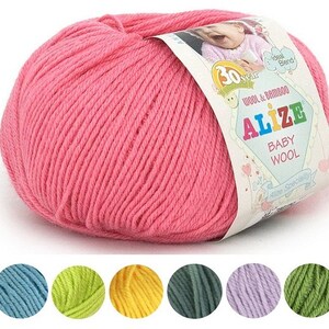 Puede incluir: Ovillo de lana rosa Alize Baby Wool. La etiqueta indica una mezcla de lana y bambú. Debajo del hilo hay muestras de color azul, verde, amarillo, verde oscuro, morado y verde claro.