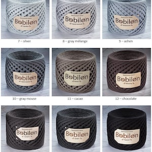 K&ouml;nnte beinhalten: Eine Sammlung von 9 Spulen Bobilon-Garn in verschiedenen Graut&ouml;nen, von hellem Silber bis zu dunklem Anthrazit. Das Garn besteht aus Baumwolle und eignet sich zum H&auml;keln und Stricken.