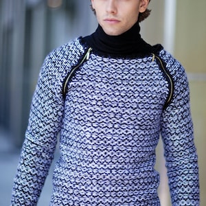 May include: A black and white patterned sweater with a mock neck and zipper details on the shoulders.