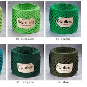 K&ouml;nnte beinhalten: Eine Sammlung von Bobilon-Garn in verschiedenen Gr&uuml;nt&ouml;nen, darunter Pistazie, gr&uuml;ner Apfel, Smaragd, Meereswelle, Dunkelgr&uuml;n und Khaki. Es gibt auch ein Lavendelgarn.