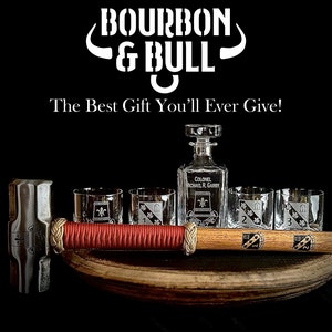 May include: A set of engraved glasses and a decanter with a bull's head logo and the text "Bourbon & Bull" and "The Best Gift You'll Ever Give!"  The glasses and decanter are on a wooden surface with a hammer.