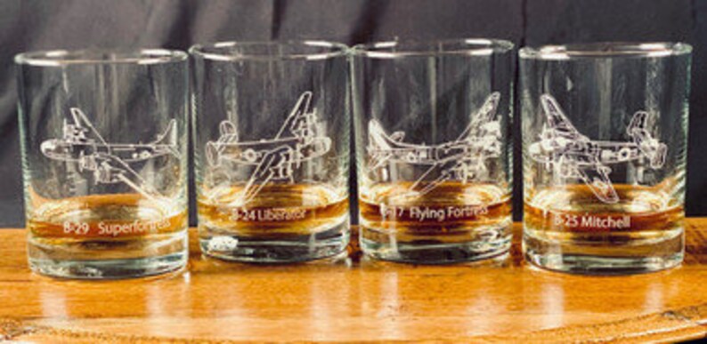 May include: Four clear glass tumblers with etched images of vintage aircraft. Each glass has a different aircraft type and name: B-29 Superfortress, B-24 Liberator, B-17 Flying Fortress, and B-25 Mitchell.