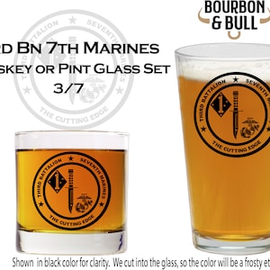 May include: Two glass drinking glasses with a frosted etching of the 3rd Battalion, 7th Marines logo. The logo is a circle with a star on each side, a knife and a Marine Corps emblem inside, and the text "Third Battalion, Seventh Marines, The Cutting Edge".