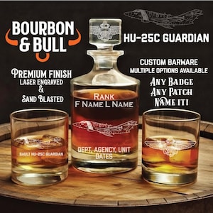 May include: A clear glass decanter and two matching glasses filled with amber liquid. The decanter has a stopper and is etched with a military emblem and the text "RANK F NAME L NAME". The glasses are etched with military aircraft and emblems. The text "BOURBON & BULL" is at the top.