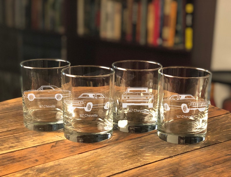Puede incluir: Cuatro vasos transparentes de vidrio con un contorno blanco de un coche Chevrolet Chevelle de 1967 grabado en cada vaso. Los vasos est&aacute;n sobre una superficie de madera.
