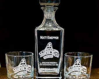 May include: A clear glass decanter with a square stopper and two matching lowball glasses. Each piece features an etched graphic of a stylized orca, the text SSN 787, and the phrase FEAR THE BLACKFISH. The decanter also displays MATT KNEPPER.
