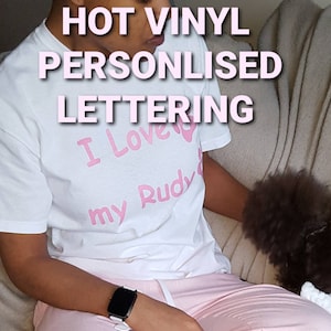 May include: A white t-shirt with pink vinyl lettering that says "I Love My Rudy".
