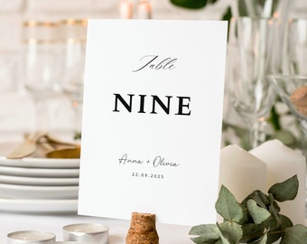May include: White table number card with black text reading "Table NINE Anna + Olivia 22.09.2025". The card is held by a cork.