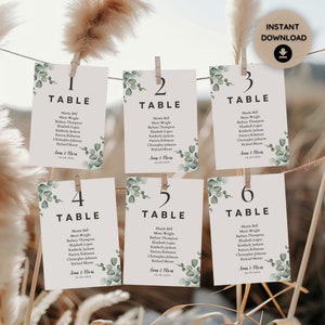 Puede incluir: Seis tarjetas de número de mesa blancas con números y texto negros. Cada tarjeta tiene un diseño de hoja de eucalipto y el texto 'TABLE' con el número correspondiente. El texto en cada tarjeta incluye los nombres 'Martin Bell', 'Maria Wrighe', 'Barbara Thompson', 'Elizabeth Loper', 'Kimberly Jackson', 'Patricia Robinson', 'Christopher Johnson' y 'Richard Moore'. El texto también incluye la fecha '22.09.2023' y los nombres 'Anna & Olaia'.
