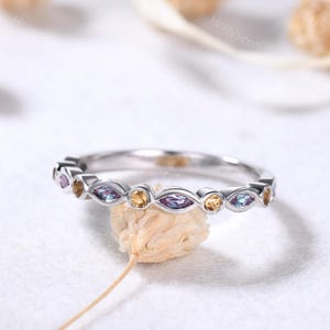 May include: A silver band ring with a row of alternating purple, blue, and yellow marquise-shaped gemstones.