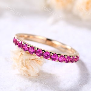 May include: A delicate gold band with a row of pink gemstones. The band is thin and has a polished finish.