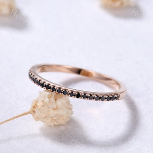 May include: A delicate rose gold band ring with a row of small black diamonds.