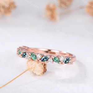 Op de afbeelding: Roségouden ring met afwisselende marquise-geslepen edelstenen in groen en blauw, afgewisseld met kleine witte stenen. De ring heeft een delicate band en een elegant ontwerp.