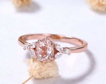 Könnte beinhalten: Ein Verlobungsring aus Roségold mit einem birnenförmigen Morganit-Mittelstück und einem Heiligenschein aus kleineren Diamanten. Der Ring ist auf einem zarten Band mit einem floralen Design gesetzt.