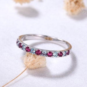 Peut inclure: Une délicate bague en argent avec une rangée de pierres précieuses bleues et roses alternées.