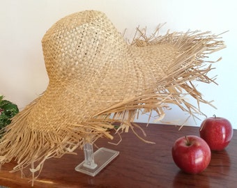 Summer hat in natural straw with wide frayed edges.