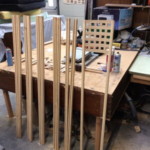 May include: A workshop table with wooden slats and a lattice panel. The slats are stacked and ready for assembly. The lattice panel is made of thin strips of wood and has a square grid pattern.