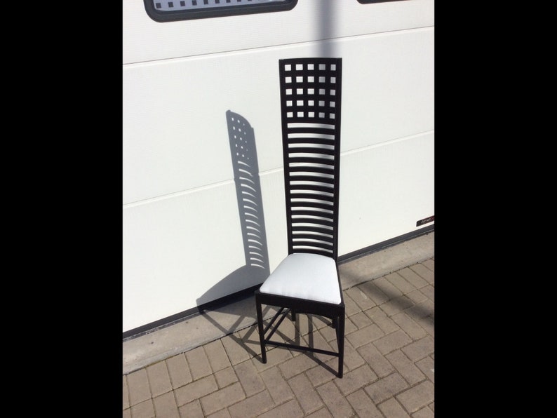 May include: A black wooden chair with a white cushion. The chair has a tall back with a geometric pattern.