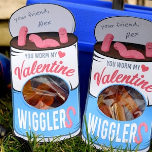 May include: Two blue and white Valentine's Day cards shaped like a can of worms. The cards have a red heart and the text "You worm my Valentine" and "Wigglers".