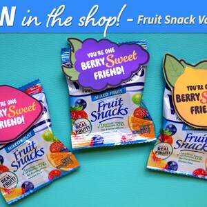 Peut inclure: Trois petits sachets de fruits secs avec des cartes sur le th&egrave;me de la Saint-Valentin attach&eacute;es. Les cartes sont en forme de fraise, de citron et de raisin. Chaque carte porte le texte "You're one berry sweet friend!" imprim&eacute; dessus.
