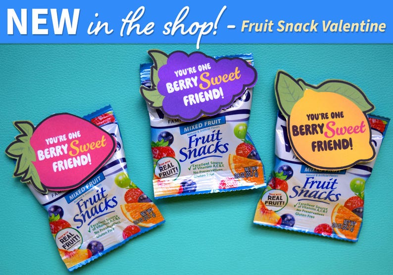 Peut inclure: Trois petits sachets de fruits secs avec des cartes sur le th&egrave;me de la Saint-Valentin attach&eacute;es. Les cartes sont en forme de fraise, de citron et de raisin. Chaque carte porte le texte "You're one berry sweet friend!" imprim&eacute; dessus.
