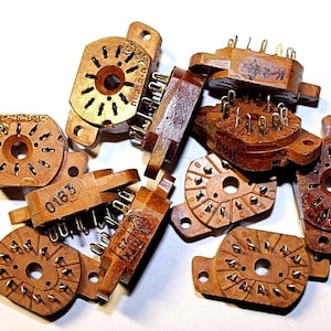 Puede incluir: Un grupo de diez interruptores rotatorios vintage de plástico marrón con contactos metálicos dorados. Los interruptores tienen números y letras impresos en ellos.