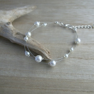 Op de afbeelding: Een delicate zilveren armband met witte parel kralen. De armband heeft een eenvoudig ontwerp en is perfect voor dagelijks gebruik.