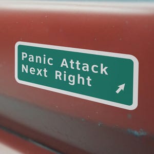 Puede incluir: Una pegatina rectangular para parachoques con fondo verde y borde blanco. El texto Panic Attack Next Right aparece en letras mayúsculas blancas, acompañado de una flecha blanca que apunta en diagonal hacia arriba a la derecha.