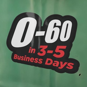 May include: A black decal with white and red text applied to a smooth, light green surface. The sticker features the bold white text 0-60, followed by the red text in 3-5 Business Days, all contained within a rounded, irregular black border.