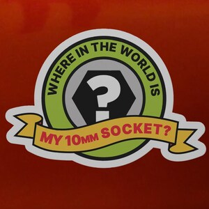 May include: A circular sticker with a green border and a black hexagon center featuring a white question mark. A yellow banner across the bottom reads "MY 10MM SOCKET?" and the text "WHERE IN THE WORLD IS" arches along the top green border.