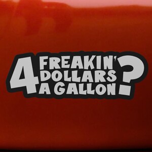 Puede incluir: Una pegatina de vinilo de color gris claro con un borde negro que presenta el texto 4 FREAKIN' DOLLARS A GALLON? en una fuente negrita y redondeada. La pegatina está aplicada sobre una superficie naranja sólida, lisa y brillante.