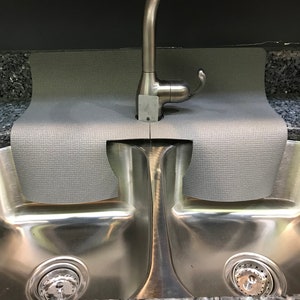 May include: A gray sink mat with a stainless steel double sink underneath. A silver faucet is mounted above the sink.