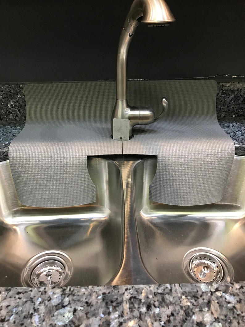 May include: A gray sink mat with a stainless steel double sink underneath. A silver faucet is mounted above the sink.