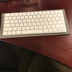 May include: A white wireless keyboard with a gray and black protective case. The keyboard has a standard layout with function keys, arrow keys, and a numeric keypad.