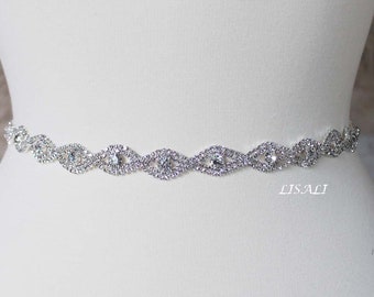 May include: A silver rhinestone belt with a wavy design. The belt is on a white mannequin.