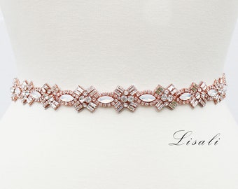 May include: Rose gold bridal belt with a floral design. The belt features clear and opal-colored crystals arranged in a repeating pattern. The belt is displayed on a white mannequin. The word "Lisali" is written in cursive on the bottom right.