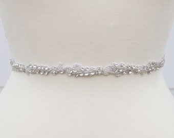 May include: A silver bridal sash with a delicate floral design and crystal embellishments.