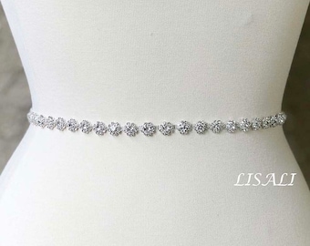 May include: A silver rhinestone belt with a delicate design. The belt is made of small, round rhinestones that are connected by a thin silver chain. The belt is perfect for adding a touch of sparkle to any outfit.