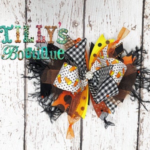 May include: A Halloween-themed hair bow with black and white checkered ribbon, orange and white candy corn ribbon, black and orange polka dot ribbon, and black mesh. The bow is tied with a black ribbon and has a rhinestone in the center.