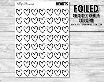 May include: A sheet of 49 black and white heart stickers. The text "HEARTS" and "FOILED CHOOSE YOUR COLOR!!!" is printed on the sheet. The text "WWW.TILLYSPLANNING.ETSY.COM" is printed at the bottom of the sheet.