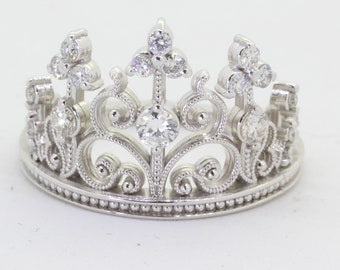 May include: A silver tiara with a delicate, ornate design and sparkling clear stones.