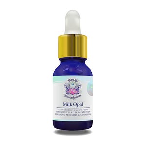 Op de afbeelding: Een blauwe glazen fles met een gouden dop en een wit etiket. Het etiket vermeldt "Shanti Kay Hawaiian Essences Milk Opal" en beschrijft de voordelen van het product.