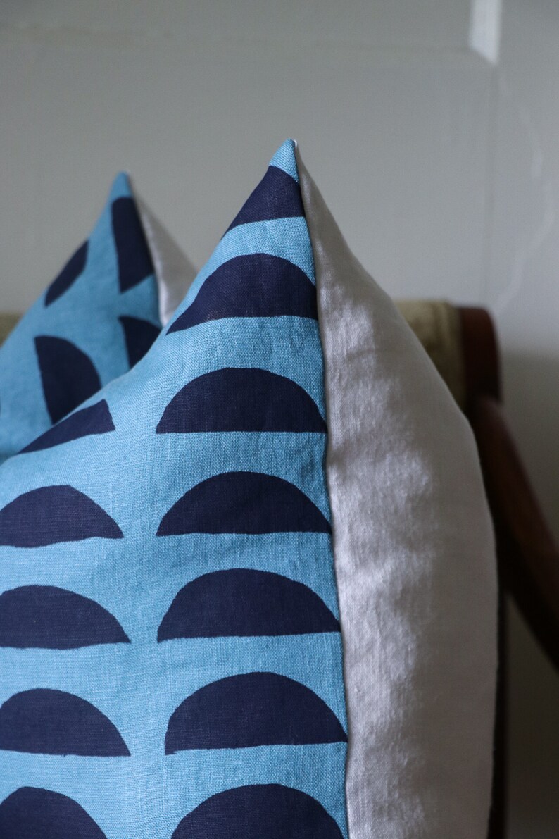 May include: A blue and navy blue pillow with a geometric pattern of half circles. The pillow is made of a soft, textured fabric.