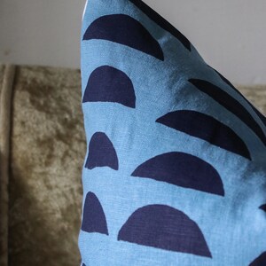 May include: A blue pillow with a pattern of dark blue half circles. The pillow is made of a soft, textured fabric.