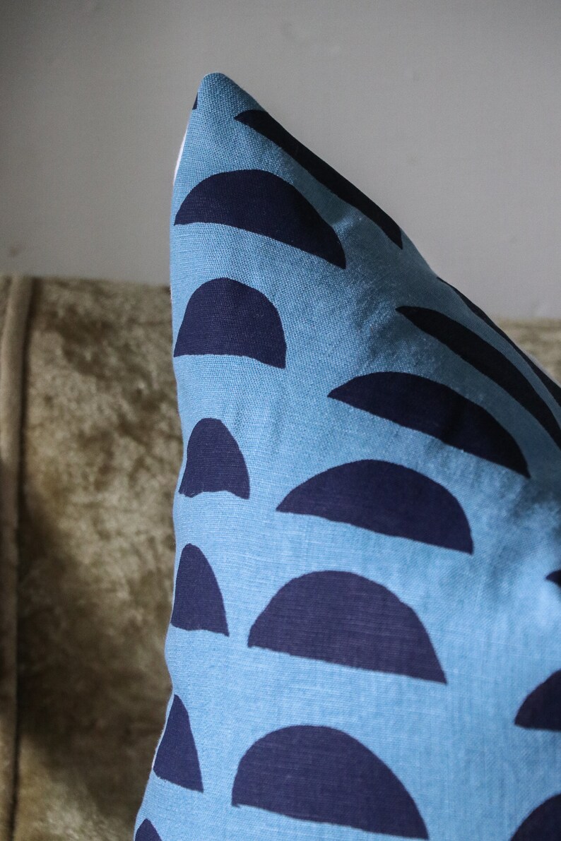 May include: A blue pillow with a pattern of dark blue half circles. The pillow is made of a soft, textured fabric.